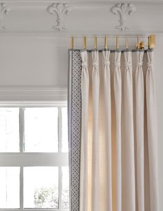 the curtains are hanging on the rod in front of the window, with gold hardware