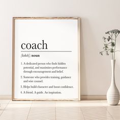 a white vase sitting on top of a wooden floor next to a poster with the words coach