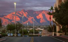 the mountains are covered in pink hues as the sun is setting on this street