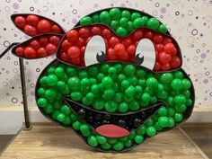 a large balloon sculpture made to look like a green alien with red eyes and nose