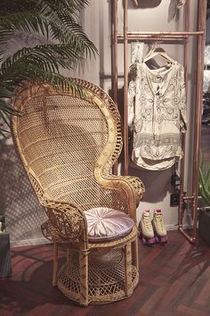 a wicker chair sitting on top of a wooden floor next to a potted plant