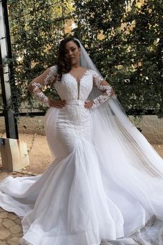 a woman in a wedding dress posing for the camera with her veil over her shoulder