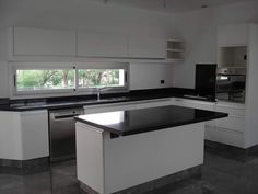 an empty kitchen with black counter tops and white cupboards on either side of the island