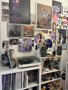 a record player sitting on top of a white book shelf filled with records and cds