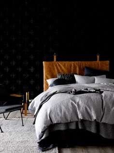 a bedroom with black walls and grey bedding in the corner, along with two chairs