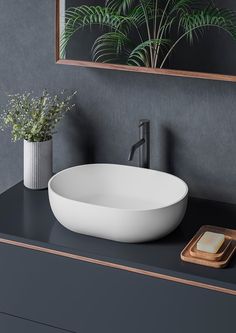 a white bowl sink sitting on top of a black counter next to a wooden tray