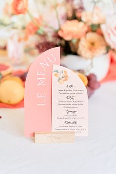 the menu card was placed on top of an orange and pink table cloth with flowers in the background