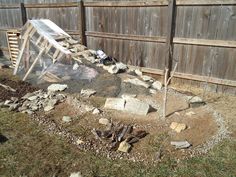 a pile of rocks sitting in the middle of a yard next to a wooden fence