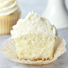 a cupcake with white frosting sitting on top of a paper muffin wrapper