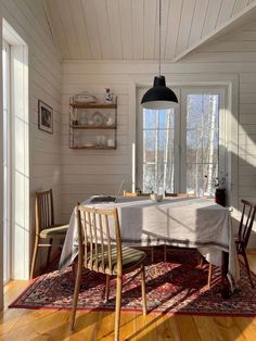 a dining room table with chairs and a rug on the floor in front of it