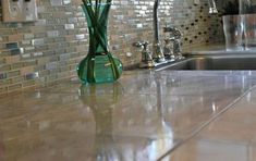 a glass vase with flowers in it sitting on a kitchen counter next to a sink