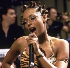 a woman singing into a microphone while wearing glasses