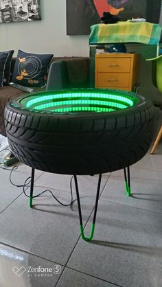 a green tire sitting on top of a metal stand in front of a couch and table