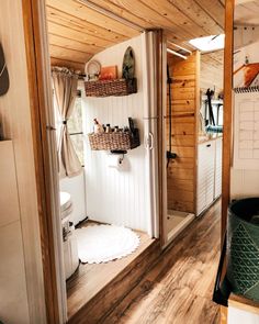 the inside of a small bathroom with wooden floors and walls, including a shower stall