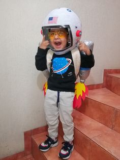 a small child wearing an astronaut's helmet and sunglasses on top of some steps