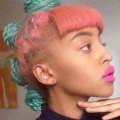 a woman with pink and green hair is taking a selfie