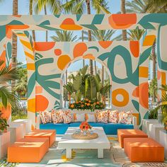 an outdoor seating area with orange, blue and white cushions on the couches in front of palm trees