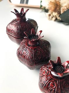 three red vases sitting on top of a white table