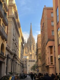 people are walking down the street in front of tall buildings with spires on them