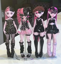 three dolls are standing next to each other on a white surface with black and pink hair