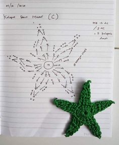 a green crocheted starfish sitting on top of a piece of lined paper