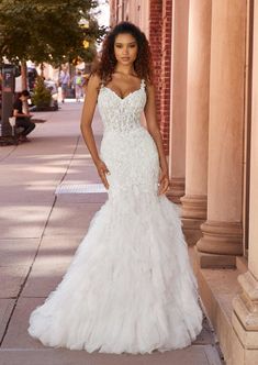 a woman in a wedding dress standing on the sidewalk