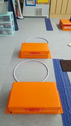 two orange boxes sitting on top of a blue mat in a room filled with toys