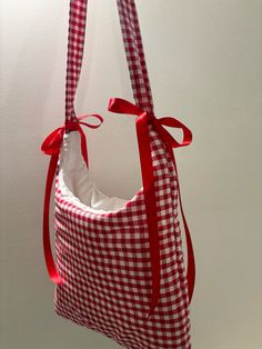 a red and white gingham bag hanging from a hook with a ribbon on it