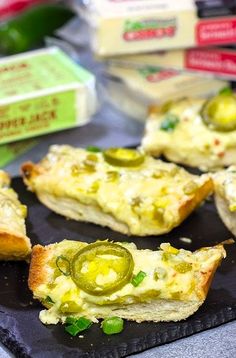 several pieces of bread with pickles and cheese on them sitting on a black plate