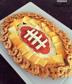 a football cheese and cracker appetizer is displayed on a white platter