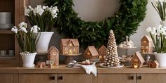 a table topped with lots of different types of christmas decorations and trees in front of a wreath