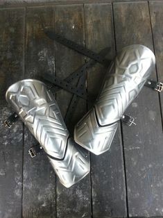 two silver motorcycle pedals sitting on top of a wooden floor next to each other