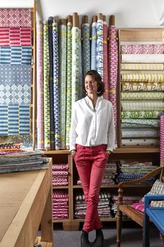 a woman is standing in front of many different colored fabrics on shelve racks