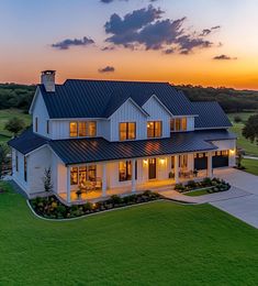 an aerial view of a large white house in the middle of a green field at sunset