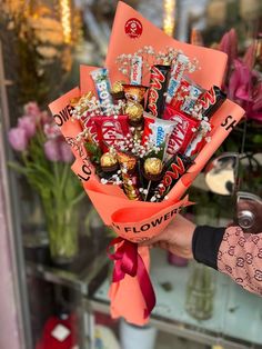 a person holding a bouquet of candy and flowers