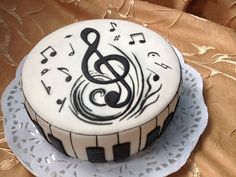 a cake decorated with music notes and piano keys on a tableclothed cloth background