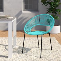 a blue chair sitting on top of a rug next to a table and potted plant