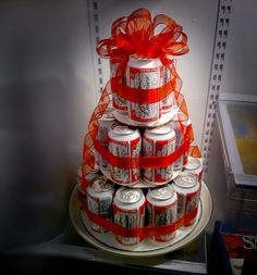 a christmas tree made out of cans and wrapped in red ribbon, sits on a plate