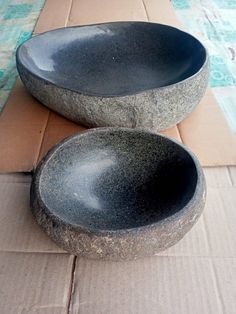 two black bowls sitting on top of a cardboard box