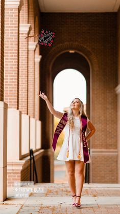 a woman in a graduation gown is throwing a pinwheel into the air with her right hand