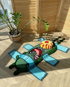 an alligator rug is on the floor next to a potted plant