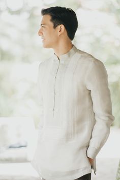 a man standing in front of a window wearing a white shirt