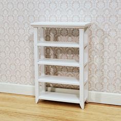 a small white shelf sitting on top of a hard wood floor next to a wall