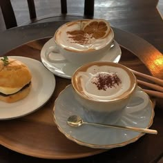 two cups of cappuccino and an orange slice on a plate with chopsticks