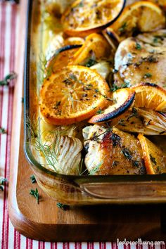 chicken and oranges in a baking dish with herbs