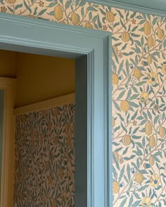 an open door in front of a wallpapered wall with lemons on it