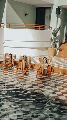 three women sitting on lawn chairs in the water