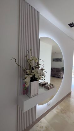 a vase filled with flowers sitting on top of a white shelf next to a mirror