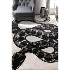 a black and white area rug with a snake on the floor next to a chair