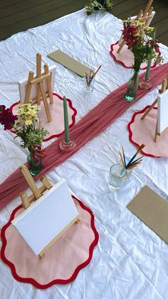 the table is set up with easels and flowers